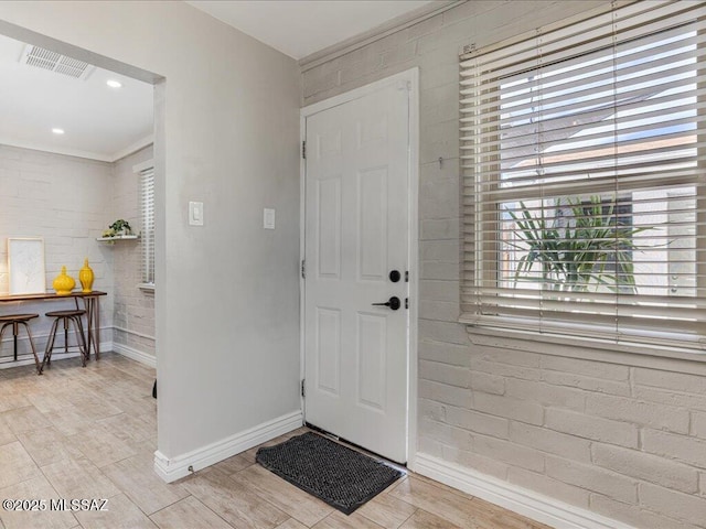 foyer entrance featuring brick wall and light hardwood / wood-style flooring