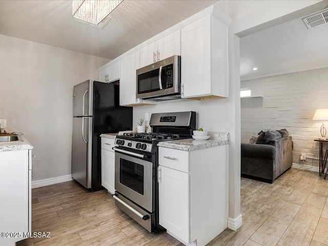 kitchen with stainless steel appliances, sink, white cabinets, and light hardwood / wood-style floors