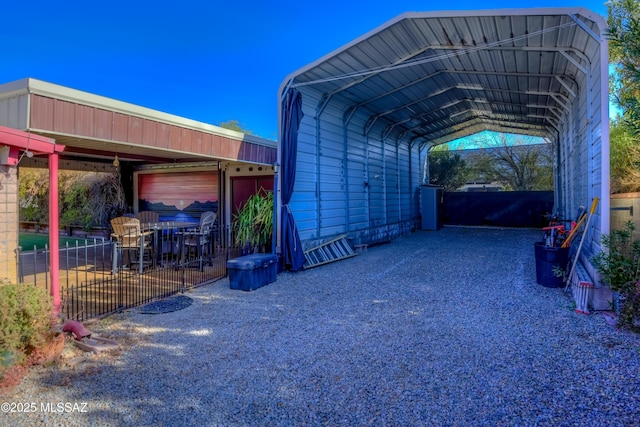 view of parking / parking lot with a detached carport, driveway, and fence