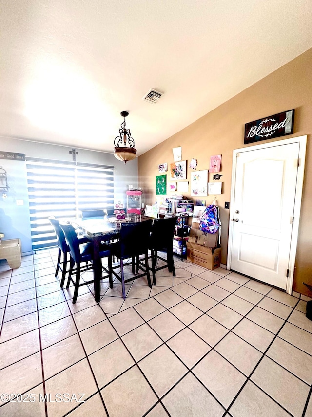 dining space with lofted ceiling, light tile patterned floors, and visible vents