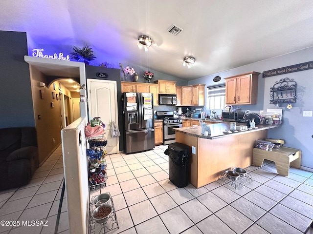 kitchen with light tile patterned floors, visible vents, gas stove, a peninsula, and black fridge