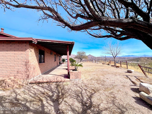 view of yard featuring a mountain view, fence, and a patio