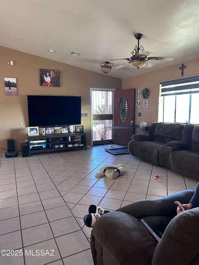 living area featuring light tile patterned floors, vaulted ceiling, and visible vents