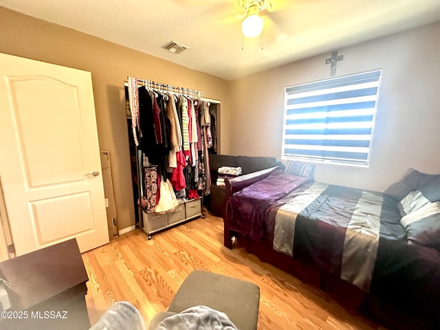 bedroom with light wood-style floors, visible vents, and a ceiling fan