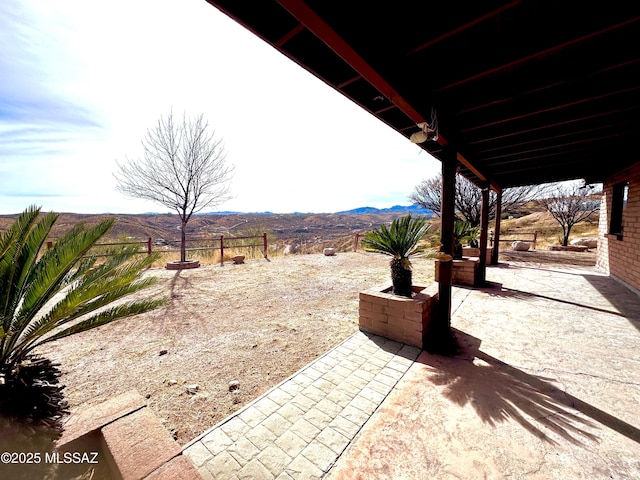 view of patio with fence and a mountain view