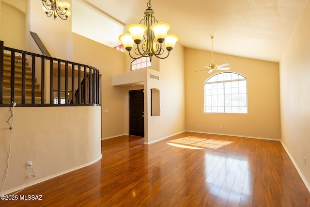 empty room with ceiling fan with notable chandelier, wood-type flooring, and high vaulted ceiling