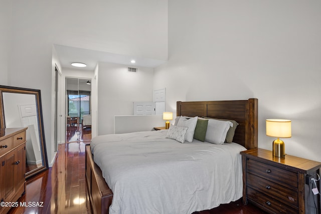 bedroom with dark wood-type flooring and a towering ceiling