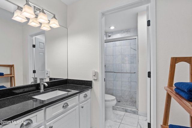 bathroom featuring a shower with door, vanity, and toilet