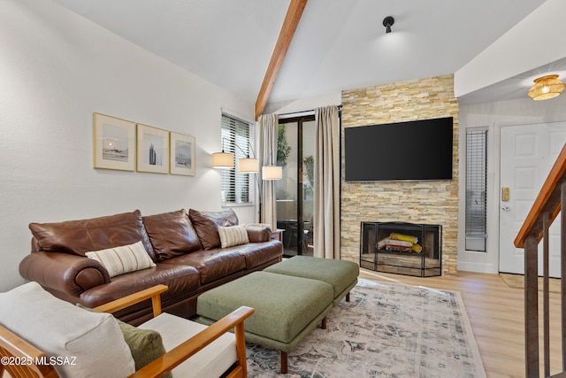 living room with vaulted ceiling with beams, a fireplace, and light wood-type flooring