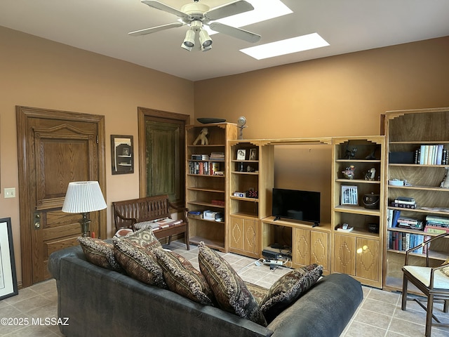 living area with a skylight, a ceiling fan, and light tile patterned flooring