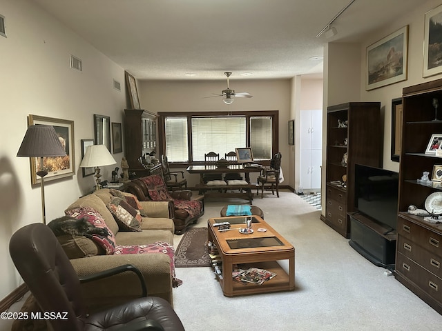 living room with light carpet, ceiling fan, visible vents, and track lighting