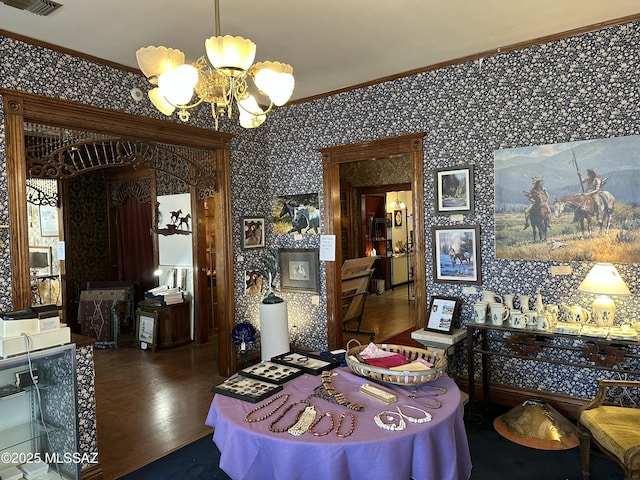 dining room featuring wallpapered walls, arched walkways, ornamental molding, dark wood-style flooring, and a chandelier