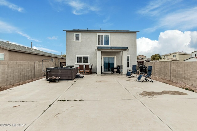 back of property with a hot tub and a patio area