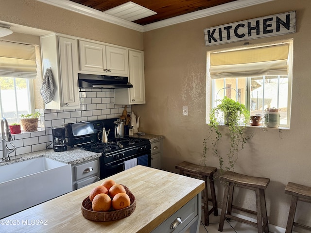 kitchen with black range with gas cooktop, sink, white cabinetry, light stone counters, and backsplash