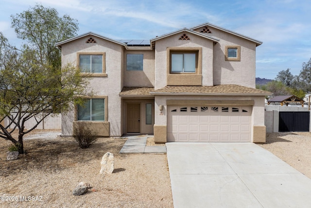 view of front of property with solar panels, fence, stucco siding, a garage, and driveway