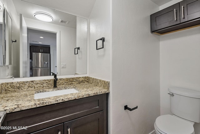 half bathroom featuring visible vents, toilet, and vanity