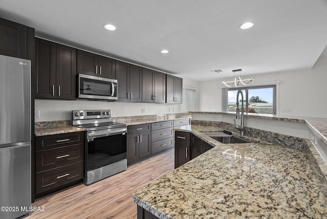 kitchen with an inviting chandelier, recessed lighting, a sink, appliances with stainless steel finishes, and light wood-type flooring