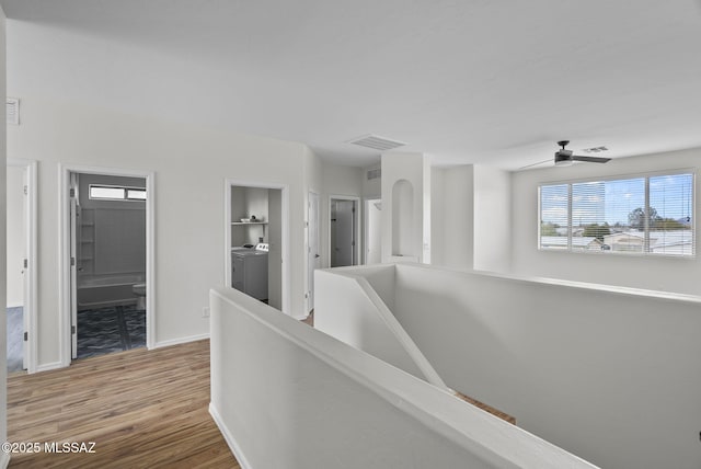 corridor featuring wood finished floors, an upstairs landing, visible vents, and baseboards