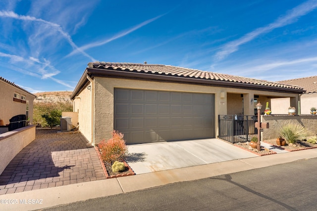 view of front of house featuring central AC unit, a tile roof, fence, driveway, and stucco siding