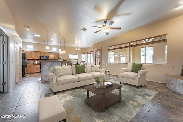 tiled living room with ceiling fan with notable chandelier