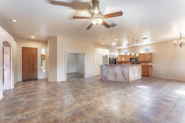 unfurnished living room featuring hanging light fixtures, ceiling fan with notable chandelier, and a center island