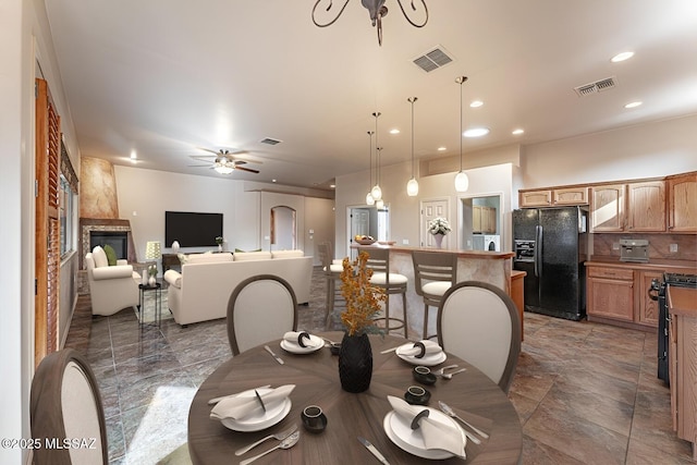 dining area with a large fireplace and ceiling fan