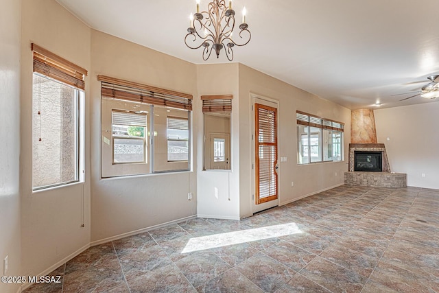 entryway with a large fireplace and ceiling fan with notable chandelier