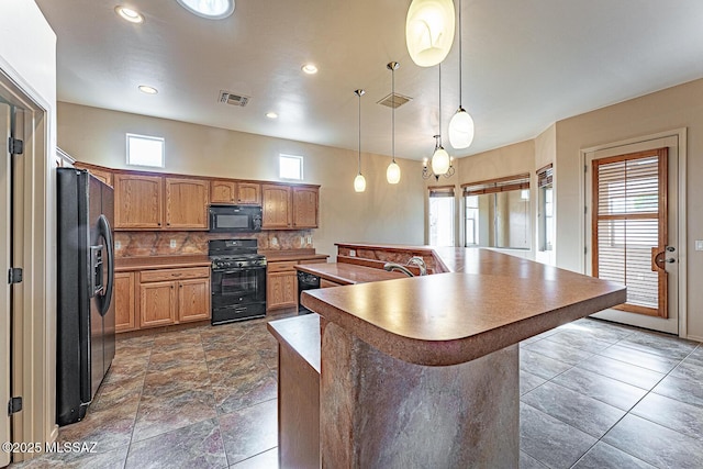 kitchen featuring an island with sink, pendant lighting, backsplash, and black appliances