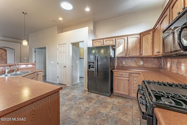 kitchen with hanging light fixtures, tasteful backsplash, sink, and black appliances