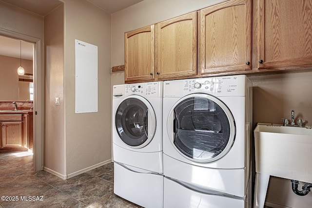 washroom with cabinets, washing machine and dryer, and sink