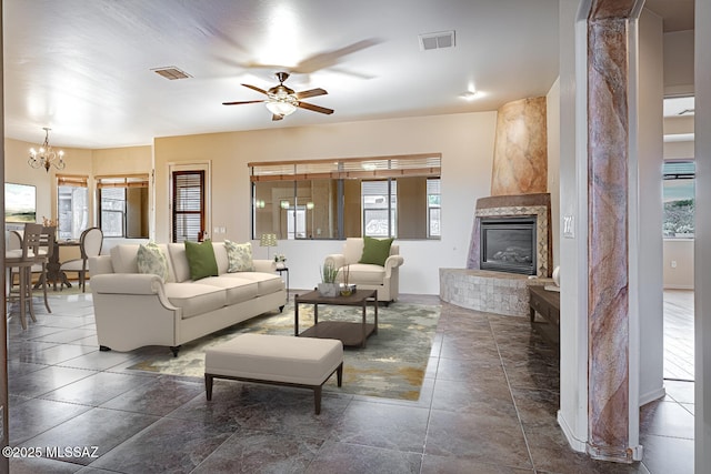 living room featuring ceiling fan with notable chandelier and a large fireplace