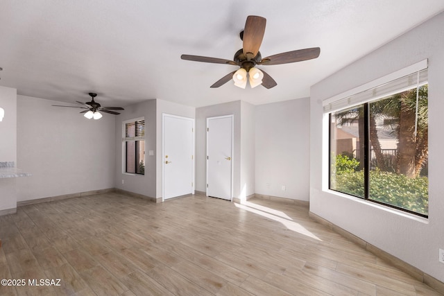 unfurnished living room featuring a healthy amount of sunlight, ceiling fan, and light wood finished floors