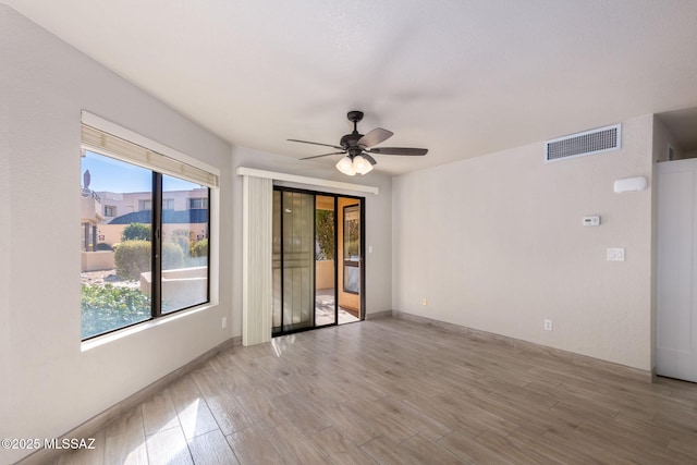 unfurnished room featuring ceiling fan, light wood-type flooring, visible vents, and baseboards