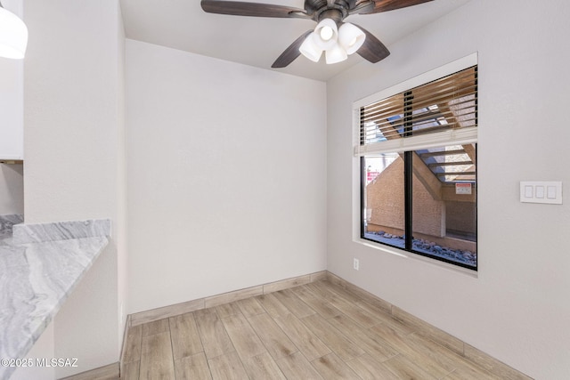 spare room featuring a ceiling fan, baseboards, and light wood finished floors