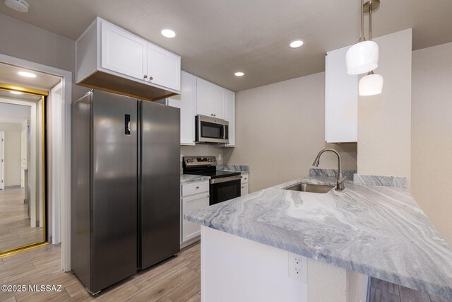 kitchen featuring appliances with stainless steel finishes, sink, white cabinets, hanging light fixtures, and light stone countertops