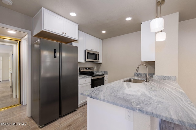 kitchen with pendant lighting, stainless steel appliances, white cabinets, a sink, and a peninsula