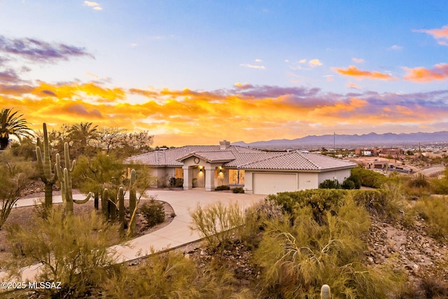4725 N Placita De Concha, Tucson, AZ 85745 - mediterranean / spanish-style home featuring a tile roof, curved driveway, a garage, a chimney, and a mountain view