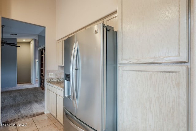 kitchen featuring light tile patterned flooring, decorative backsplash, ceiling fan, light stone counters, and stainless steel refrigerator with ice dispenser