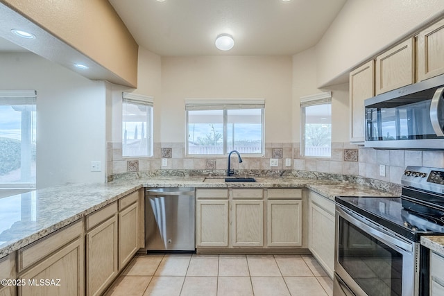 kitchen featuring light tile patterned flooring, sink, light brown cabinets, appliances with stainless steel finishes, and decorative backsplash