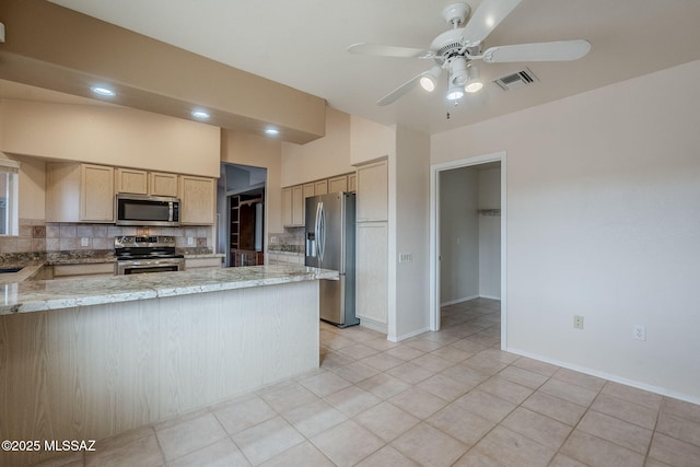 kitchen featuring stainless steel appliances, light stone counters, tasteful backsplash, light brown cabinetry, and kitchen peninsula