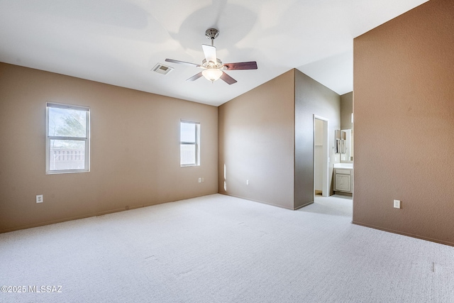 unfurnished room with vaulted ceiling, plenty of natural light, light colored carpet, and ceiling fan