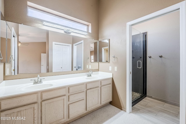 bathroom featuring a shower with door and vanity