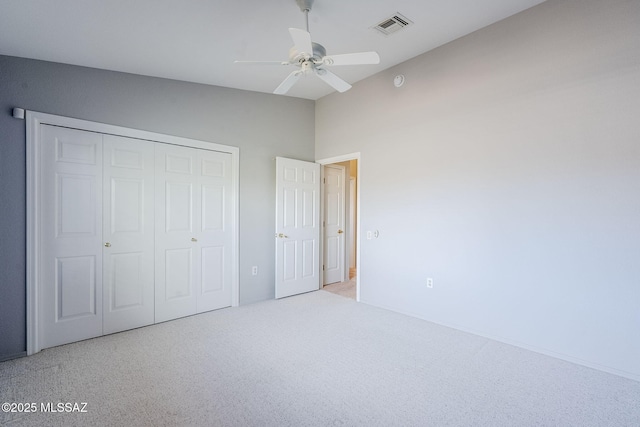 unfurnished bedroom with ceiling fan, light colored carpet, vaulted ceiling, and a closet