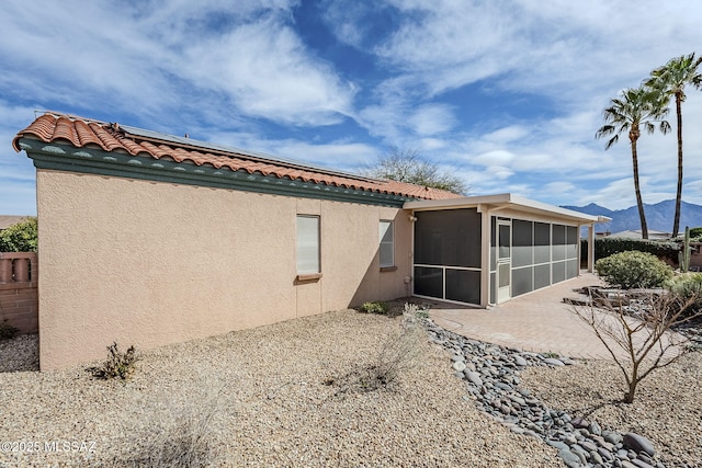 rear view of house featuring a sunroom, a patio area, a mountain view, and solar panels