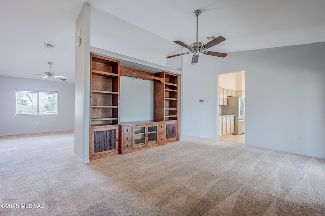 unfurnished living room with lofted ceiling, light carpet, ceiling fan, and built in shelves