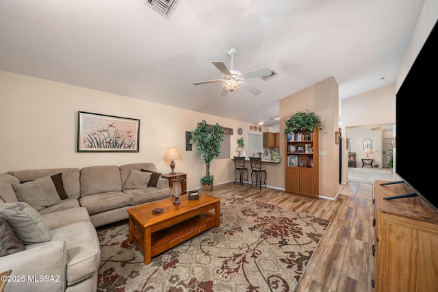 living room with lofted ceiling, ceiling fan, and light wood-type flooring