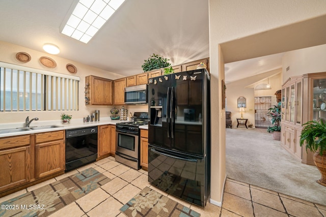 kitchen with sink, lofted ceiling, black appliances, and light colored carpet