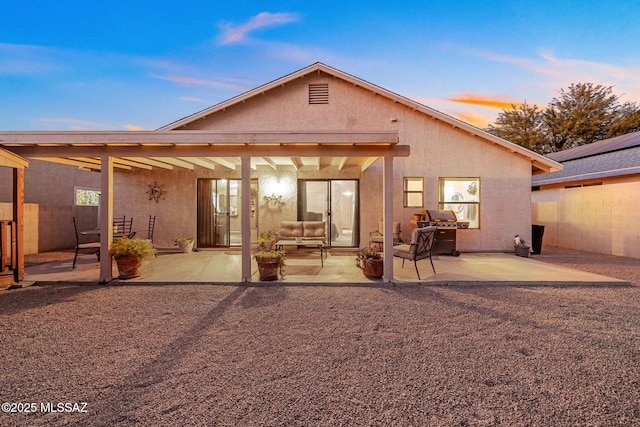 back house at dusk featuring a patio area