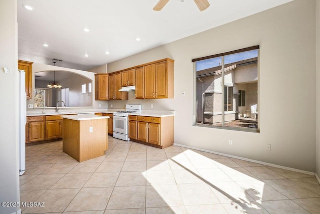 kitchen with ceiling fan with notable chandelier, white gas range, a center island, light tile patterned floors, and kitchen peninsula