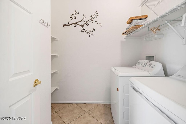 clothes washing area with light tile patterned flooring and washer and clothes dryer